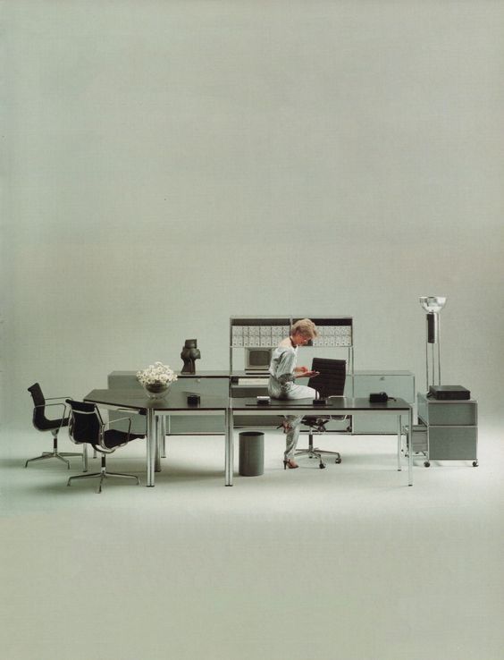 Minimal office furniture system, a worker perched at a long desk