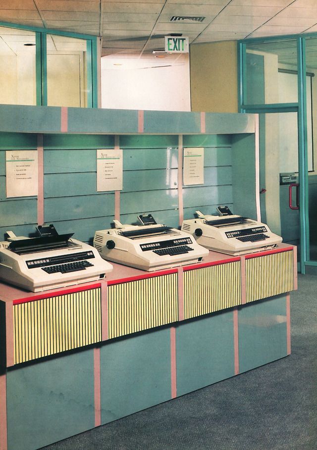 Row of beige electric typewriters on a pastel showroom counter